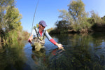 Close-up of a spool of RIO Fluoroflex Strong Tippet, 30 yards, used for fly fishing lines and leaders, with a trout in the background.