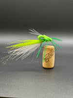 Fishing lure with green and white feathers on a cork base against a dark background