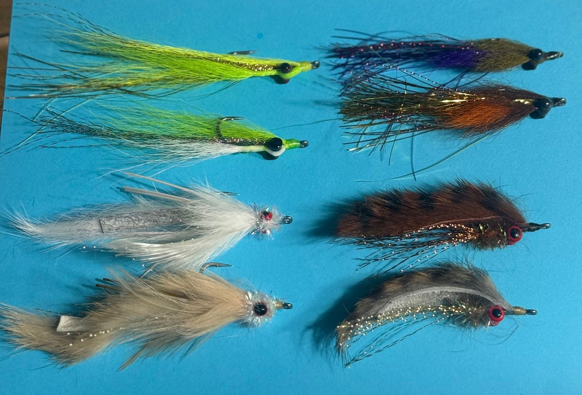 Assorted Clouser's fly fishing lures for redfish, seatrout, and smallmouth bass from Clouser's Fly Shop, displayed in a tackl