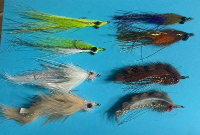 Assorted Clouser's fly fishing lures for redfish, seatrout, and smallmouth bass from Clouser's Fly Shop, displayed in a tackle box.