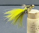 Fishing fly with yellow body on a cork stopper against a gray background