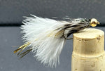 Fly fishing lure with white and black feathers on a cork stopper against a dark background