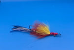 Fishing fly with red and yellow body on a blue background