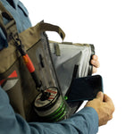 Person holding a fishing bag with tackle and phone, on a white background