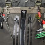 Close-up of a gray bag with various fishing tools attached, including a keychain and a small plant.