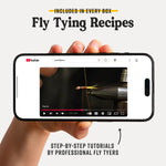 Hand holding a smartphone displaying a YouTube video on fly tying with text about included recipes and tutorials.