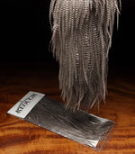 Close-up of Keough Grizzly Saddle natural fly tying material by Clouser's Fly Shop, showing the textured feather with brown and tan hues.