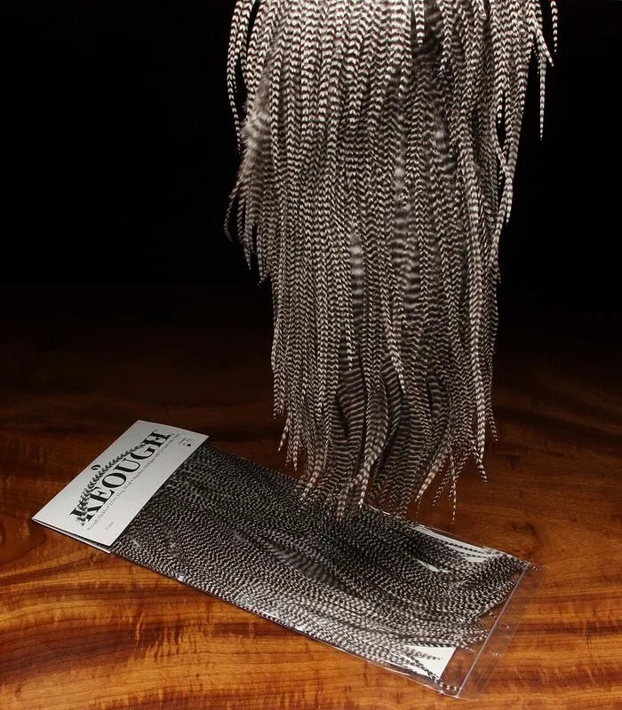 Close-up of Keough Grizzly Saddle natural fly tying material by Clouser's Fly Shop, showing the textured feather with brown and tan hues.